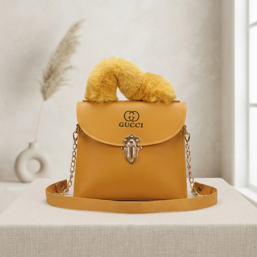 A mustard yellow Gucci handbag with a fluffy yellow handle, gold-tone hardware, and a matching shoulder strap, displayed on a light beige fabric-covered table with a soft neutral background.